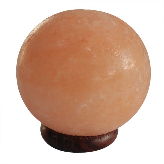 Lampe boule lumineuse en cristal de sel de l'Himalaya aux reflets orangés, posée sur un grand socle en bois. Ozora.