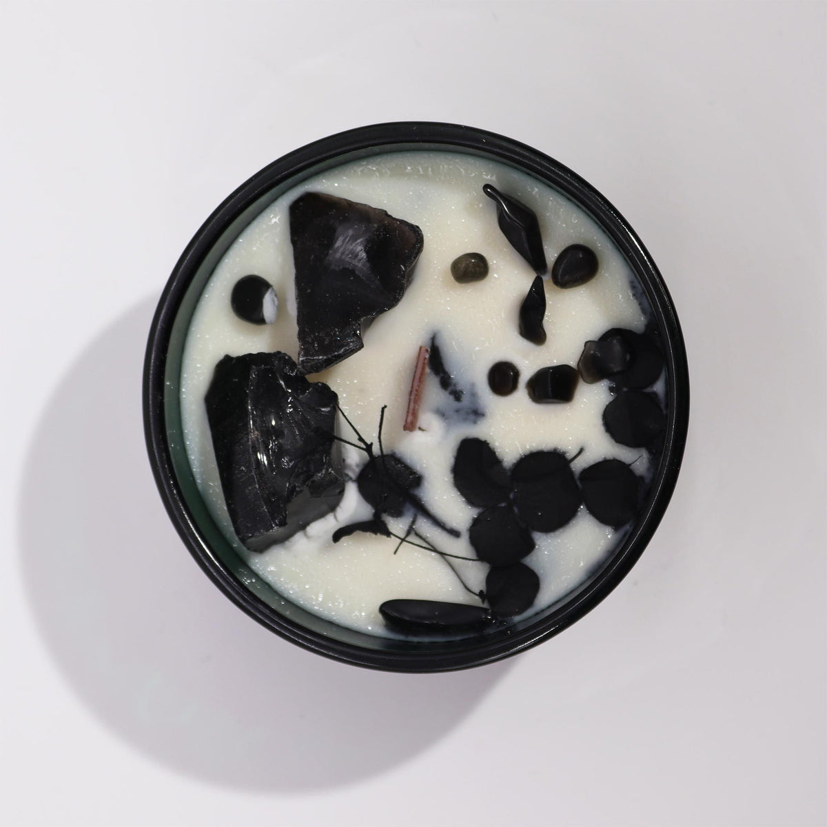 Vue rapprochée de la bougie Château de Cèdre décorée d’obsidienne noire et de fleurs séchées. Ozora