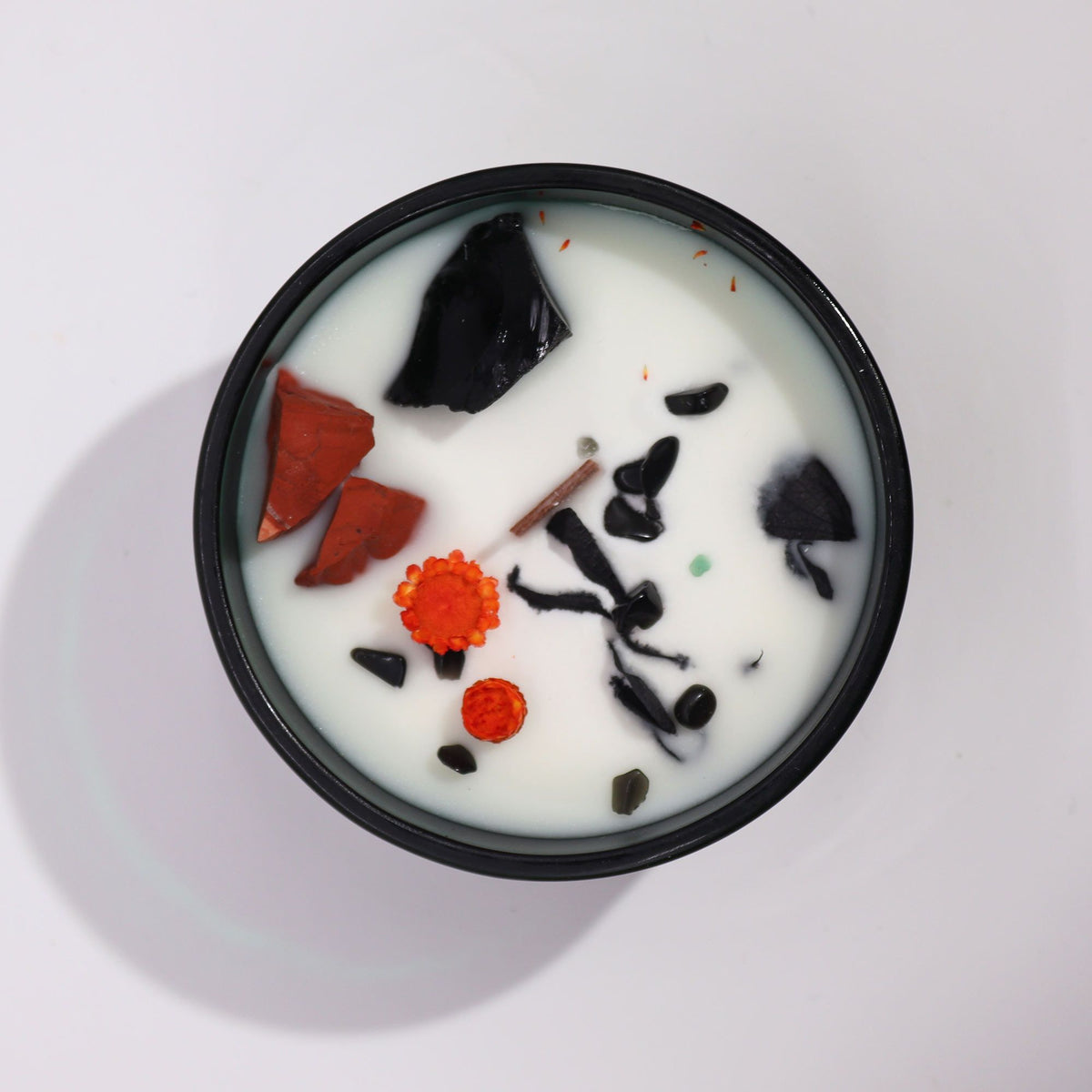Vue de dessus de la bougie « Le Diable » avec jaspe rouge, agate noire, éclats de pierres et fleurs séchées. Ozora