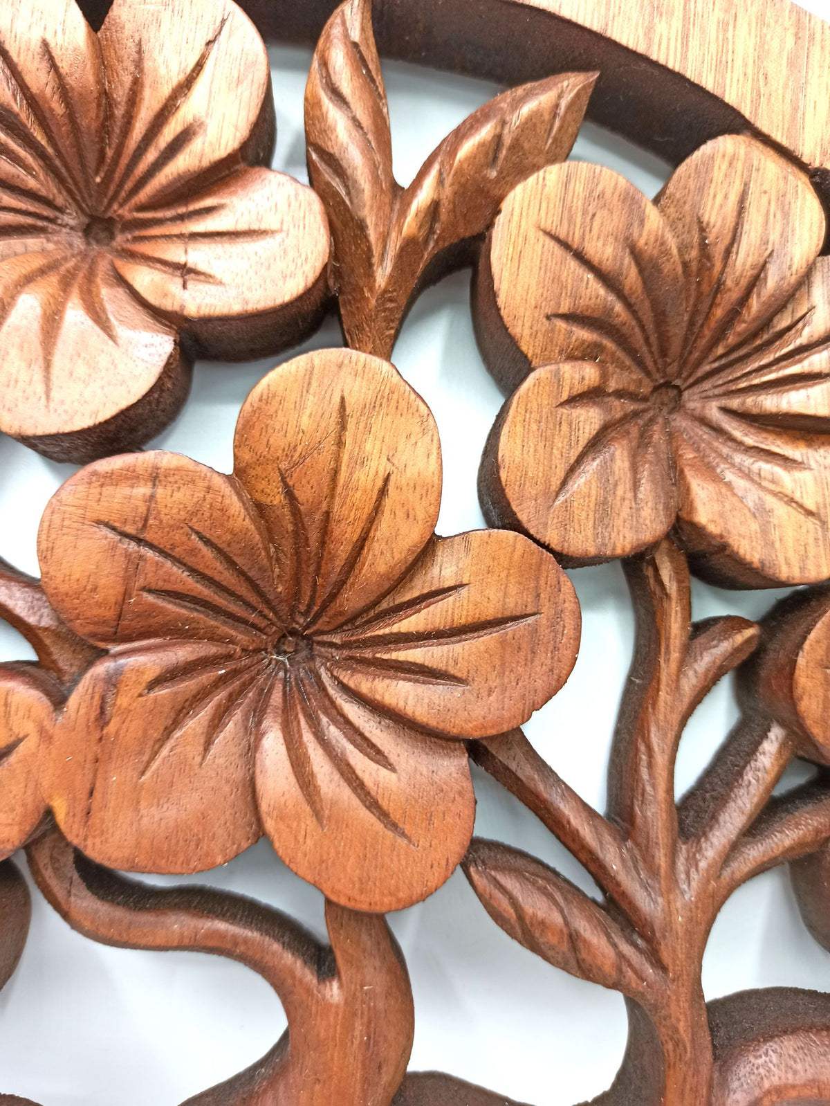 Tableau mural rond en bois de suar chantourné représentant un Arbre de Vie aux branches ornées de fleurs de frangipanier sculptées, diamètre 40 cm. Ozora.