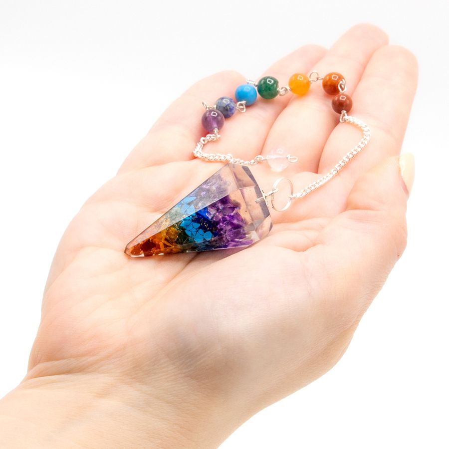 Pendule en forme de pointe réalisé en orgonite, il présente de jolies nuances colorées inspirées des sept chakras. Ozora