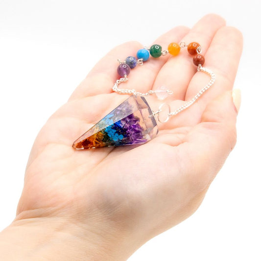 Pendule en forme de pointe réalisé en orgonite, il présente de jolies nuances colorées inspirées des sept chakras. Ozora