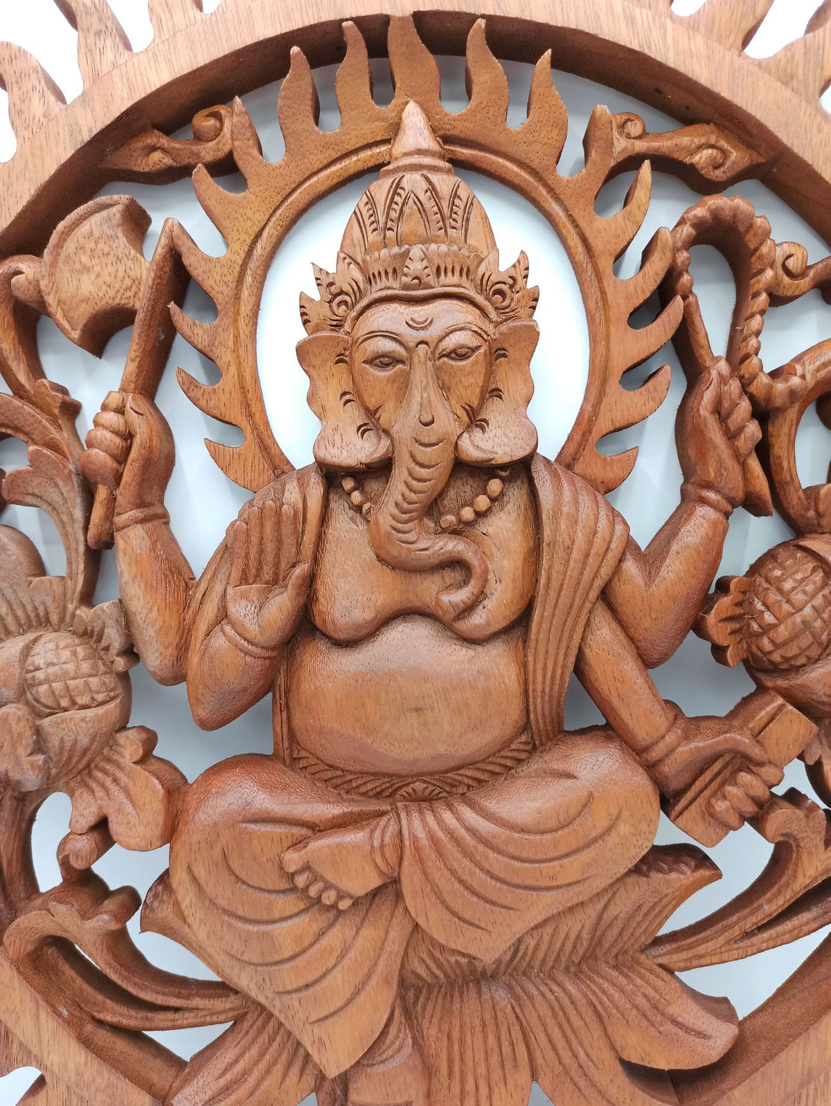 Tableau mural rond en bois de suar chantourné représentant Ganesh, divinité hindoue à tête d'éléphant, avec motifs sculptés ajourés, diamètre 40 cm. Ozora.