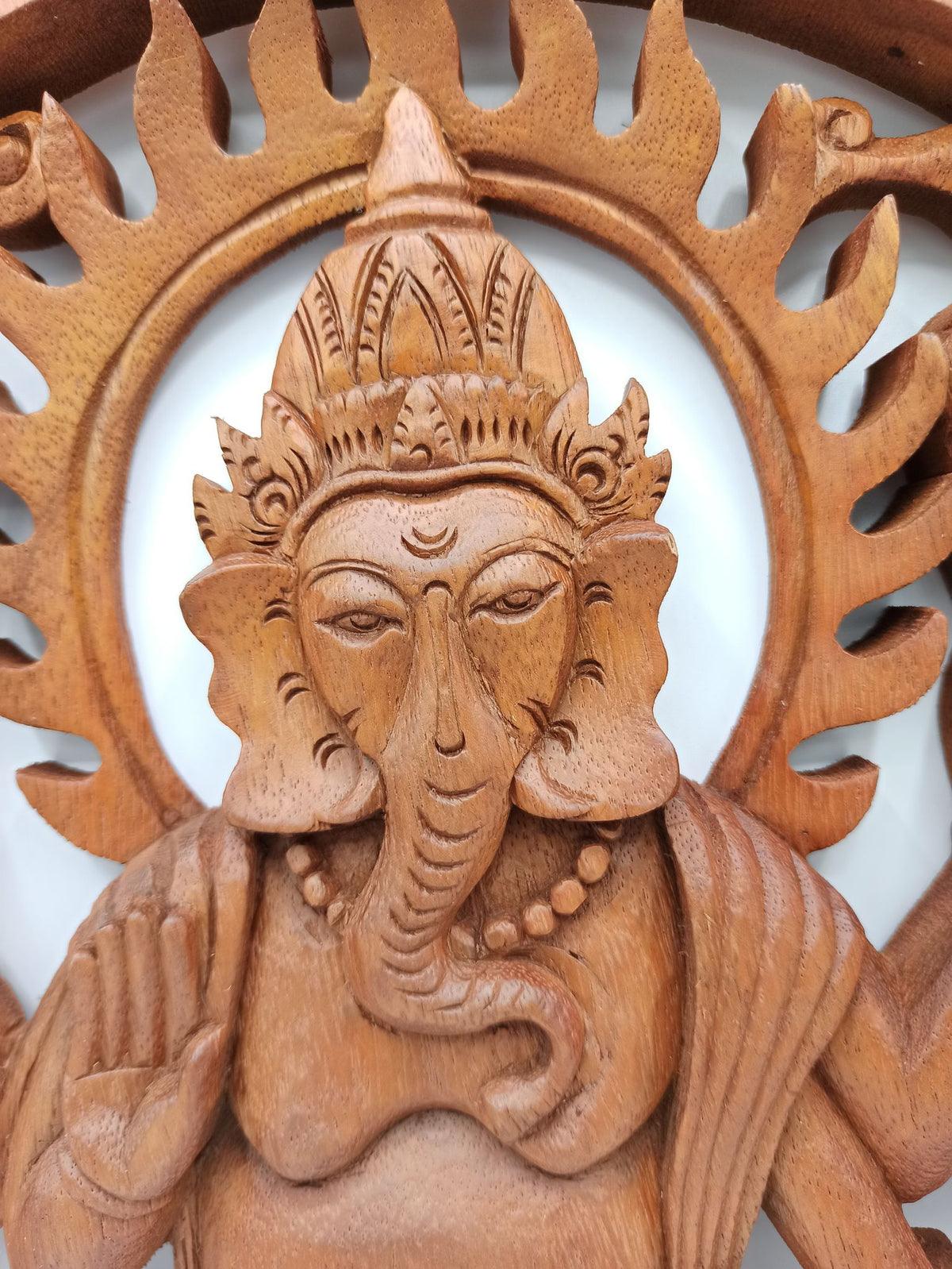 Tableau mural rond en bois de suar chantourné représentant Ganesh, divinité hindoue à tête d'éléphant, avec motifs sculptés ajourés, diamètre 40 cm. Ozora.